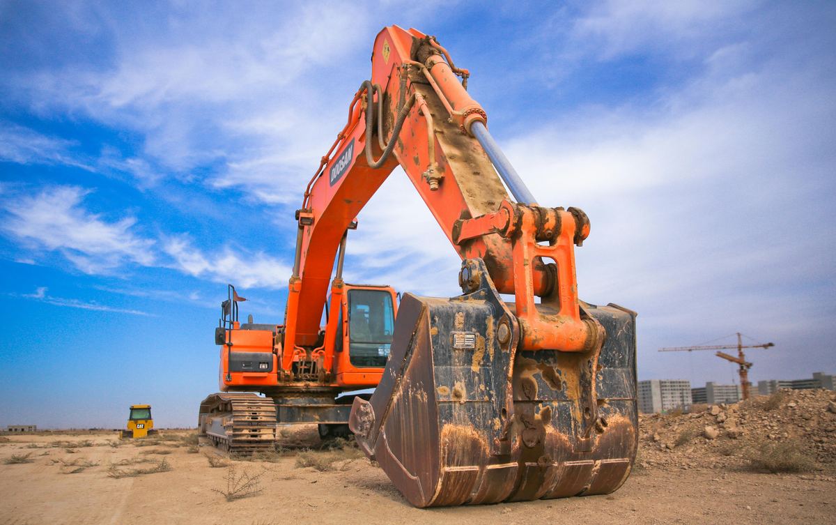 Orange excavator at construction site — equipment financing vs leasing guide